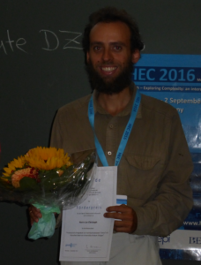 Preisträger Jan Christoph mit Urkunde und Blumenstrauß während der HEC-Tagung
